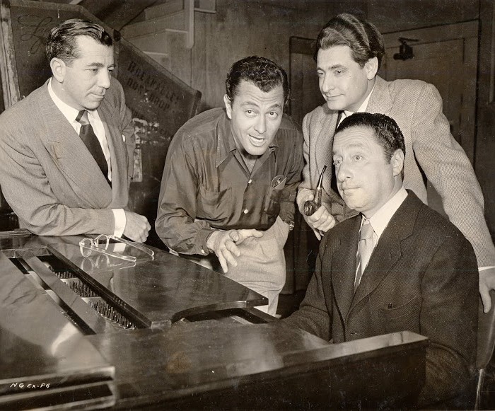 On the set of Casbah.  Around the piano, from left to right: producer Nat Goldstone, actor-singer Tony Martin, lyricist Leo Robin and composer Harold Arlen.