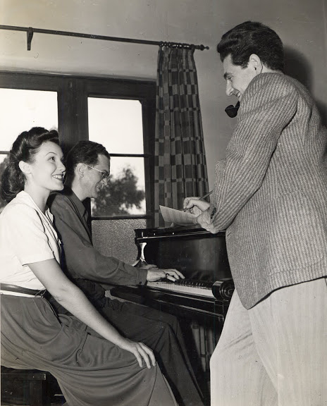 Leo Robin and Ralph Rainger at the piano with actress and dancer, Eleanore Whitney, in their bungalow on the Paramount lot, rehearsing a song for College Holiday, 1936.