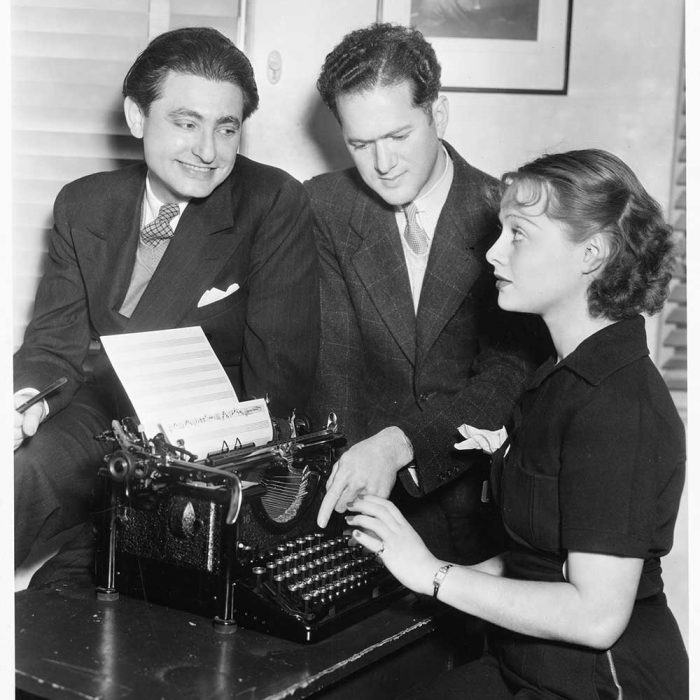 Leo Robin and Ralph Rainger with actress and dancer, Eleanore Whitney, try out the tune typing machine, a revolutionary score-writing machine, with some new songs for Three Cheers for Love, in which Miss Whitney starred