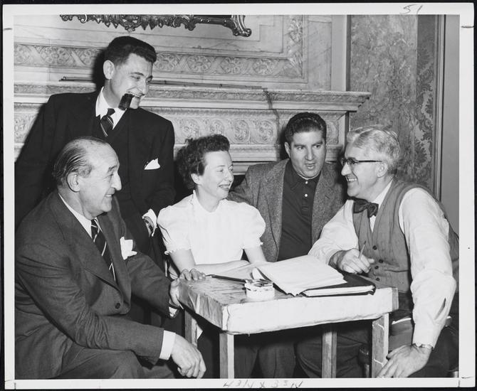 A 1954 photograph from the Museum of the City Of New York of an elite group of theatrical legends with songwriter Leo Robin. Standing is lyricist Leo Robin and sitting around the table 
from left to right: playwright and stage director Joseph Fields, dancer and choreographer Agnes De Mille (Her father William C. deMille and her uncle Cecil B. DeMille were both Hollywood directors.), playwright and librettist Jerome Chodorov and stage director and producer Shepard Traube