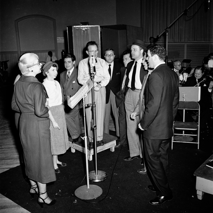 Backstage on the set of Gentlemen Prefer Blondes in 1949. From left to right: Carol Channing, Alice Pearce, lyricist Leo Robin, show producer Herman Levin, and other members of the cast -- Manny Sachs, Eric Brotherson, Jack McCauley, and George S. Irving listening to Jule Styne at the microphone.